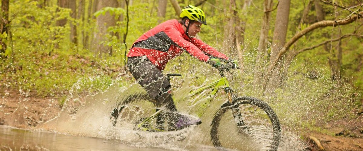 Cyclocross biker riding through creek, West Virginia