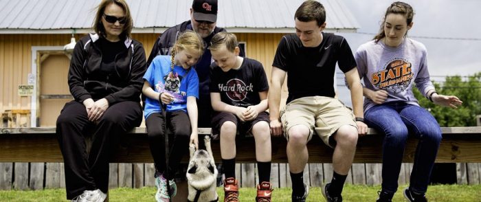 Family sitting on fence with pug in West Virginia