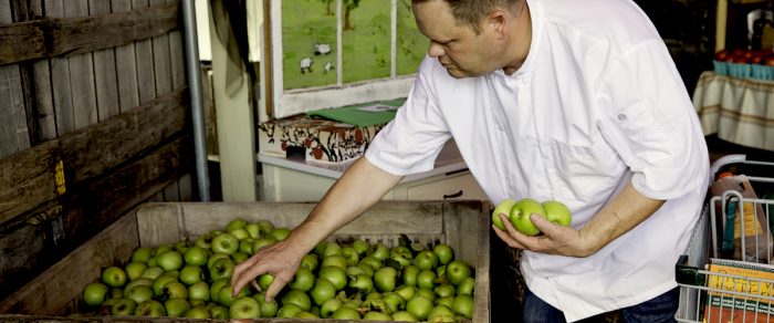 A chef picks Granny Smith apples from a crate. Farm-fresh cuisine from West Virginia