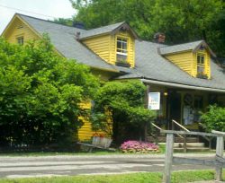 The Hutte Swiss Restaurant, a yellow clapboard cottage with dormers and wildflowers in Helvetia, West Virginia