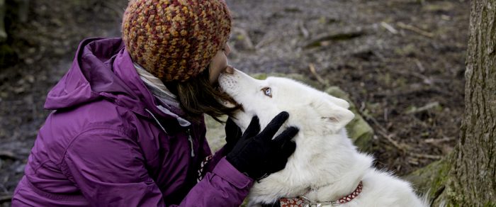 Young woman getting licked in face by white dog with blue eyes, West Virginia