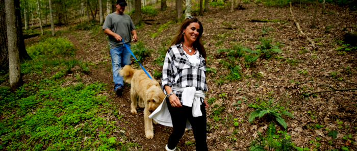 A couple with a dog hiking through woods at Twin Falls State Park, WV