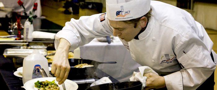 A young male chef assembles dinner at Cast Iron Cook-off, WV