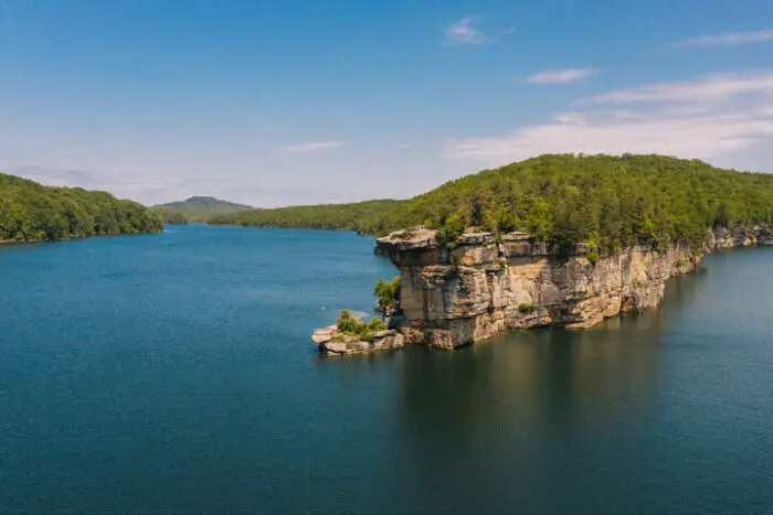 Rock cliff peninsula surrounded by blue lake and forested hills