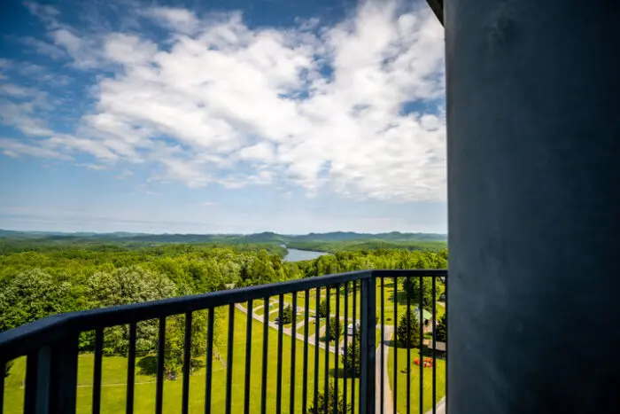 View from a balcony overlooking green landscape with river and distant hills