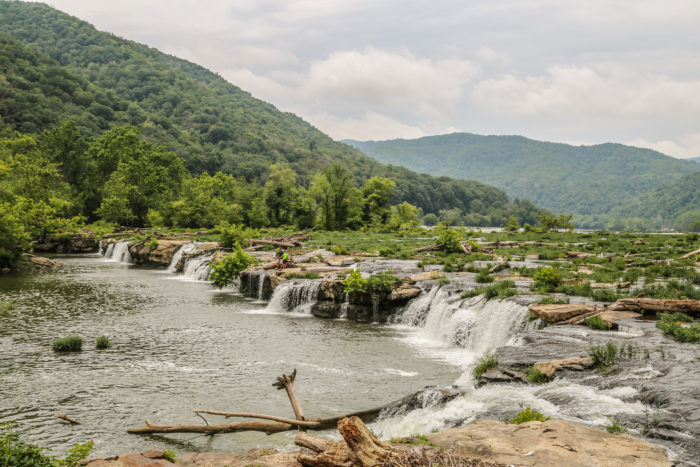 Sandstone Falls along the New River surrounded by tall green mountains and lush trees