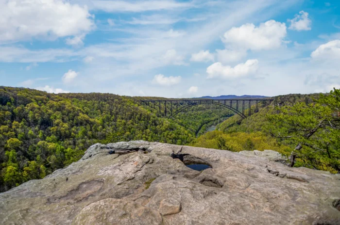 Rocky overlook with bridge spanning a forested valley in the distance