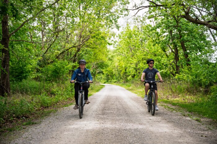 two bicycle riders on a rail trail during the spring